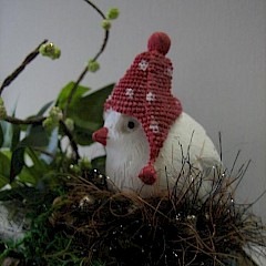 Schattig hé, dit vogeltje met rood mutsje, kerststukje op boomstronk.
